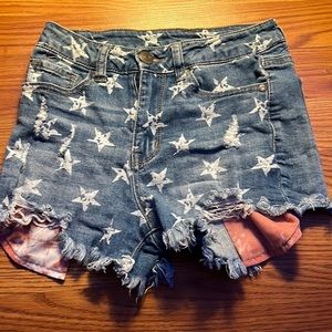 Jean shorts with white stars and pink and white tie dye pockets.